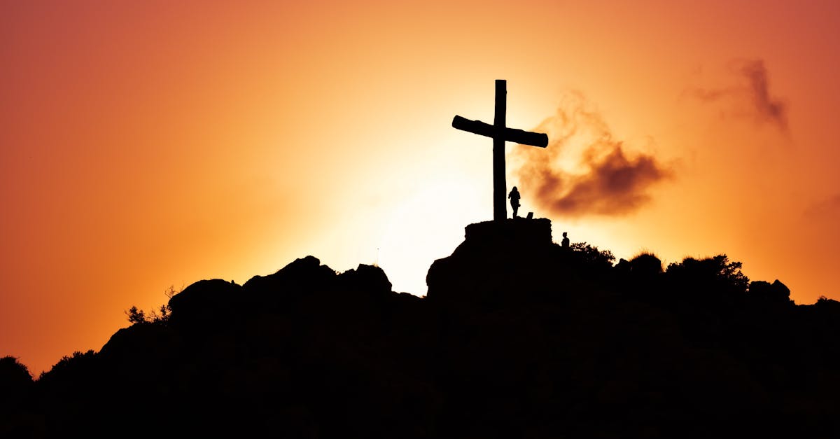 Majestic silhouette of a cross on a hill during a vivid sunset, symbolizing spirituality.