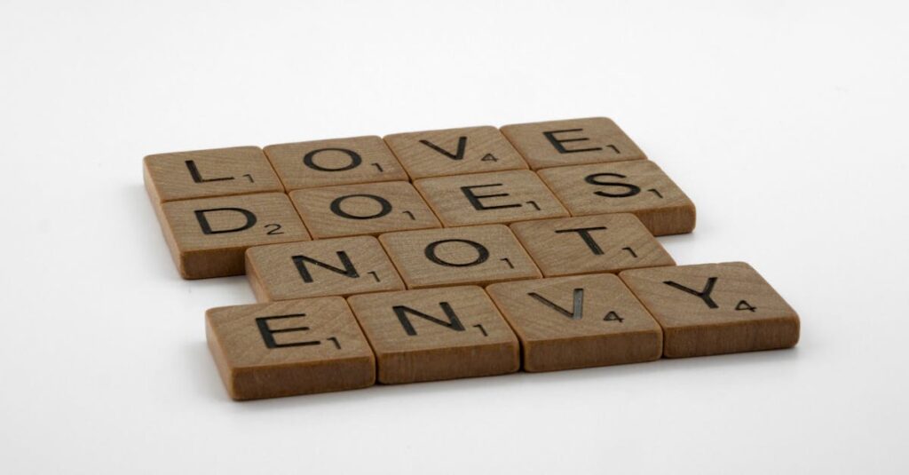 Inspirational quote 'Love Does Not Envy' spelled with Scrabble tiles on white background.