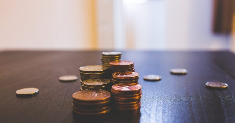 Close-up of various coins stacked on a dark table indoors.