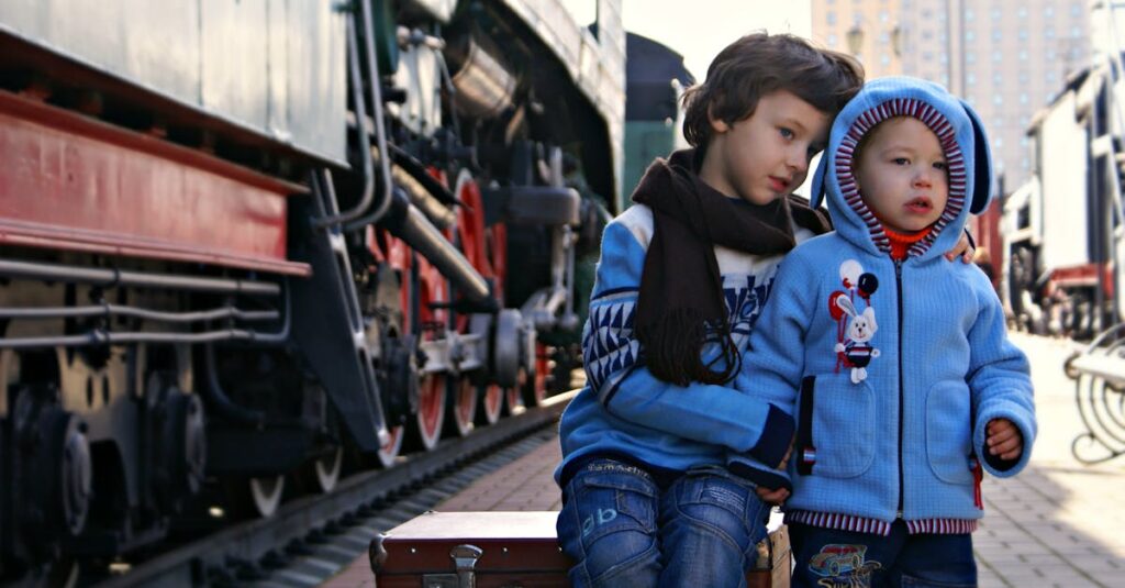 Two young boys sitting by a vintage train, waiting at the station.
