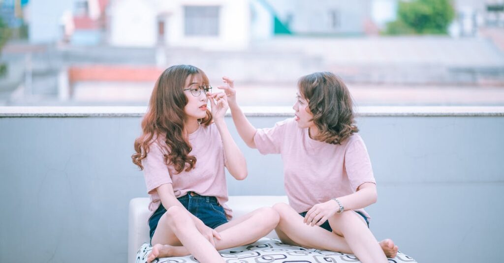 Two sisters in casual outfits laughing and interacting during a sunny day on a rooftop.