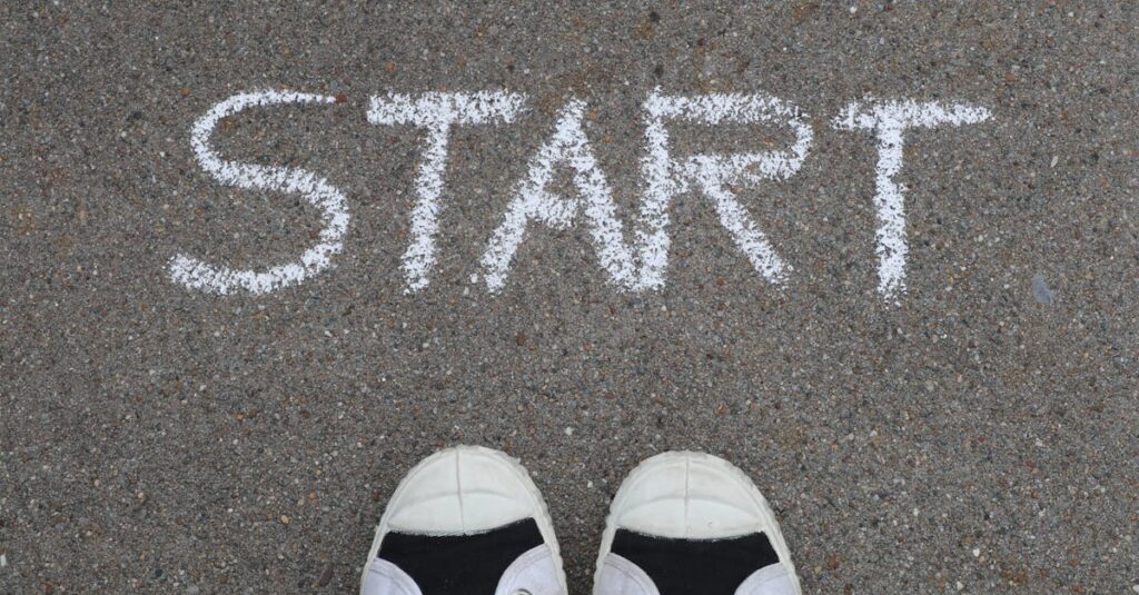 Close-up of sneakers and a 'START' chalk drawing on pavement, symbolizing new beginnings.