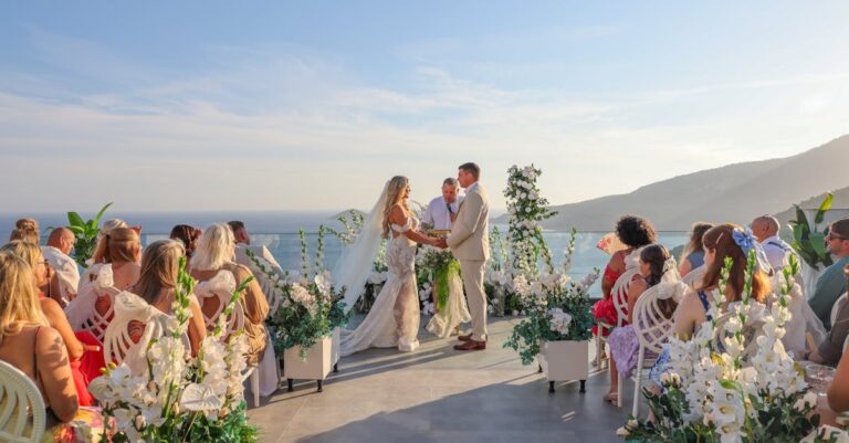 Elegant outdoor wedding ceremony with ocean view and floral decor.