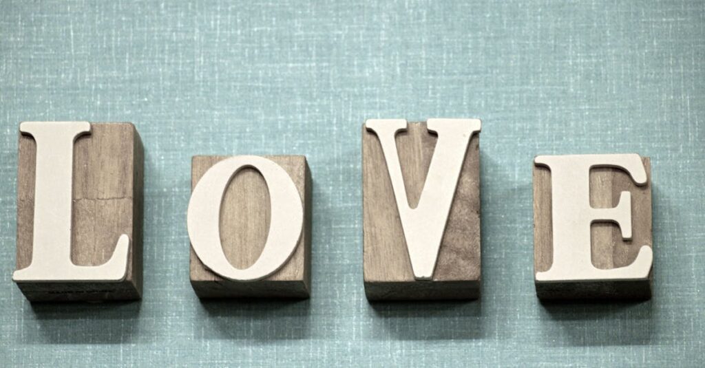 Wooden block letters spelling 'love' on a textured blue background, ideal for creative projects.