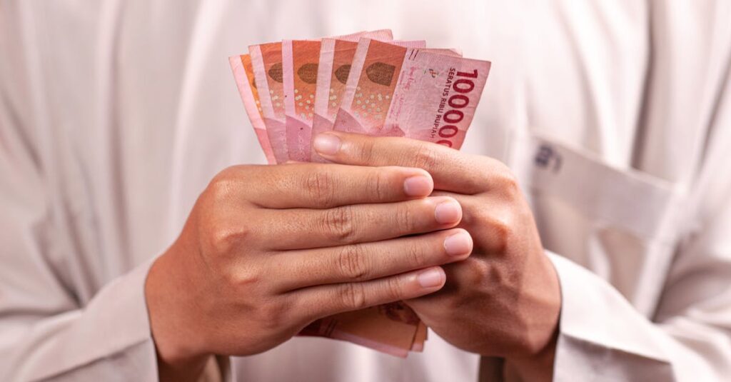 Close-up of hands holding 100,000 Indonesian Rupiah notes, symbolizing wealth and finance.