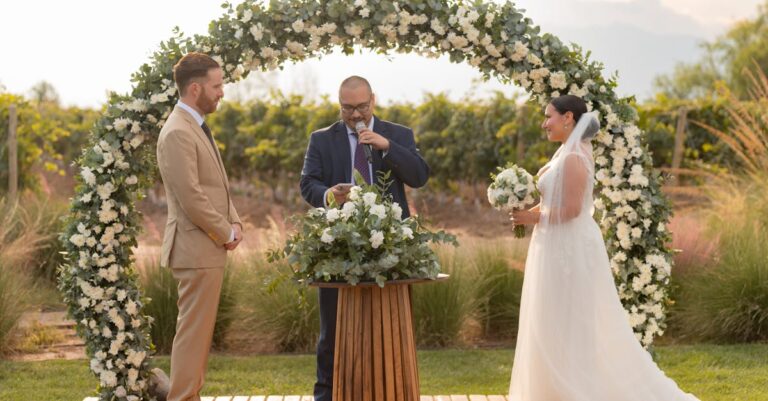 Bride and groom exchange vows under a floral arch in Mendoza, Argentina vineyard.