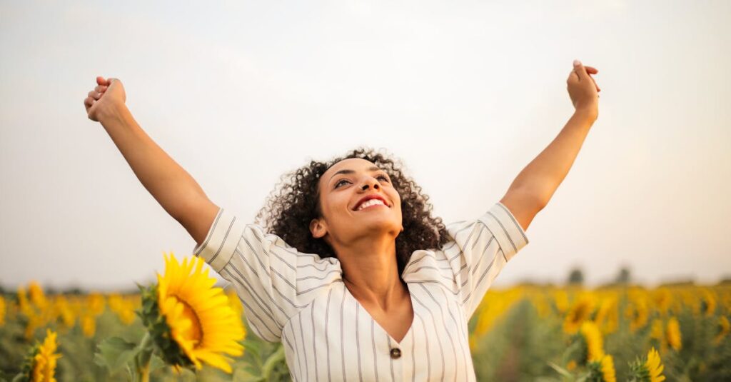 pexels-photo-3756168-3756168 Joyful woman with arms raised in a sunflower field, embracing freedom and happiness.
