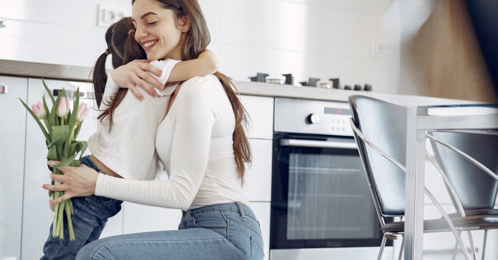 A joyful mother-daughter hug in a modern kitchen, holding tulips.