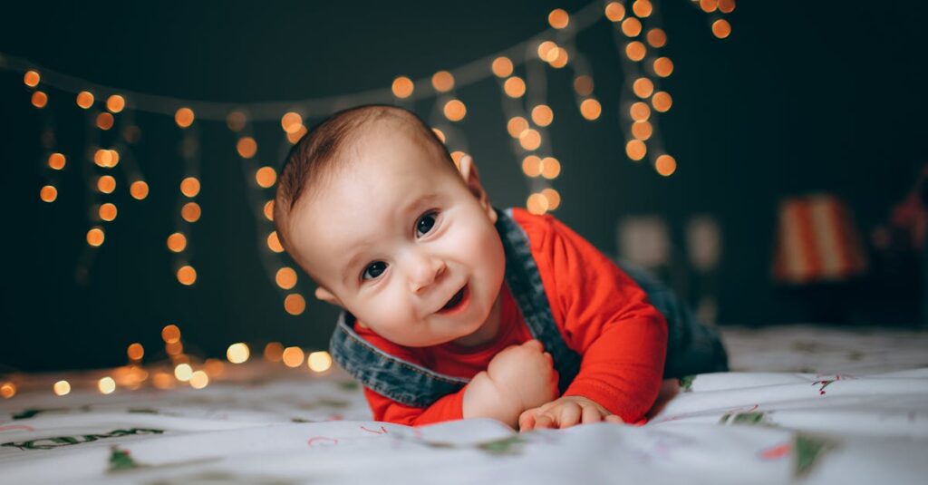 Adorable little boy lying on bed against bright Christmas lights in cozy room
