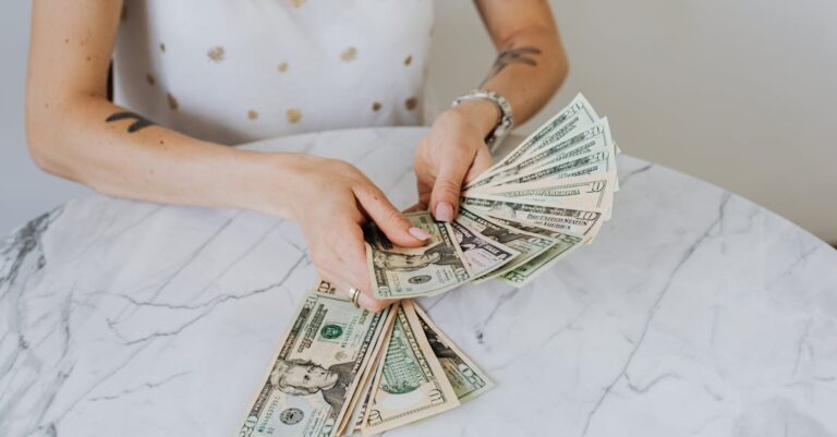 Close-up of a person counting US dollar bills on a luxurious marble table, symbolizing wealth and finance.