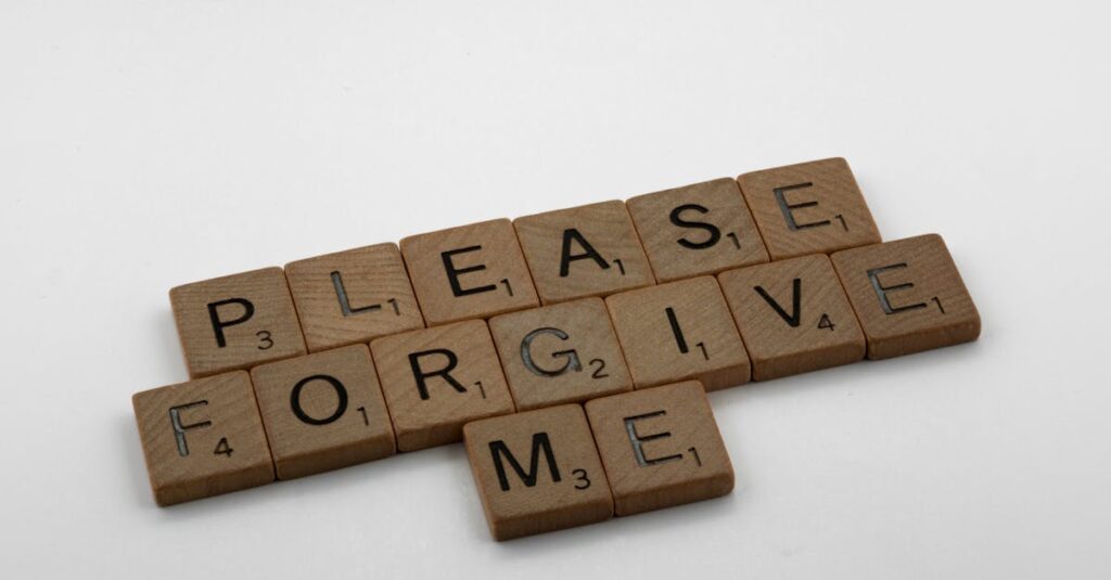 Wooden Scrabble tiles spelling 'Please Forgive Me' on a white surface, emphasizing forgiveness.