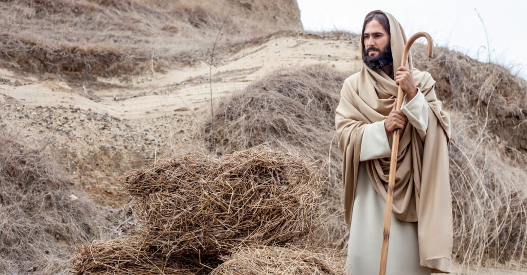 pexels-photo-7360548-7360548 A person dressed in a biblical costume holding a staff beside hay bales in an arid landscape.