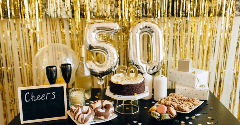 Stylish 50th birthday party setup with cake, balloons, gifts, and champagne amidst golden decorations.