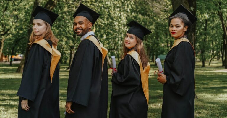 A celebratory group of diverse graduates wearing caps and gowns outdoors, holding diplomas.