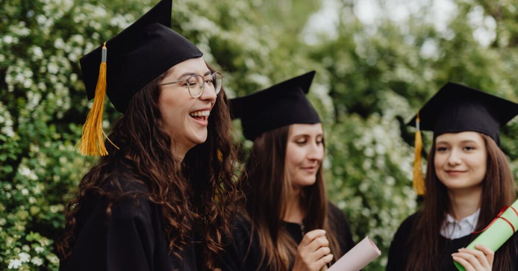 Three young women celebrating their graduation outdoors with diplomas and mortarboards.