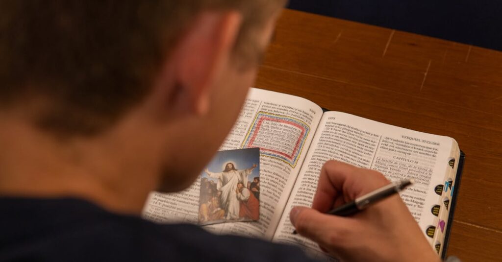 A person makes notes while reading a Bible with a photo of Jesus, focusing on study and faith.