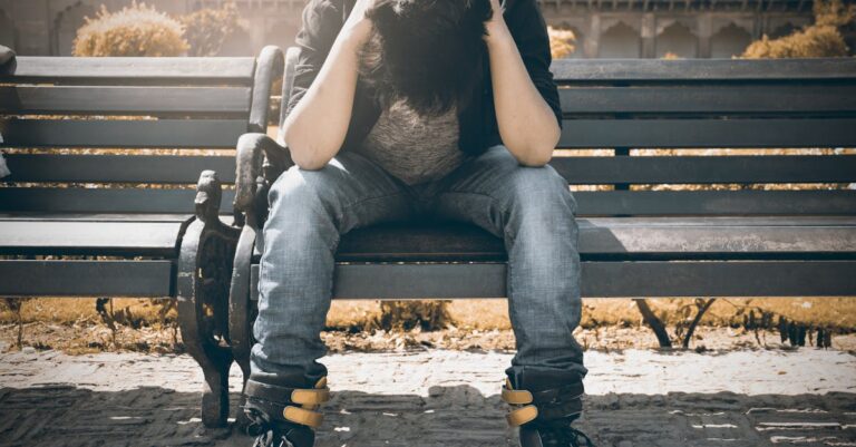 Man sitting alone on a bench in Agra, displaying signs of stress and loneliness.