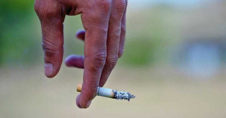 Detailed image of a hand holding a cigarette, signifying smoking habits and health risks.