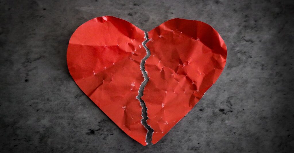 A torn red paper heart symbolizing heartbreak and lost romance.