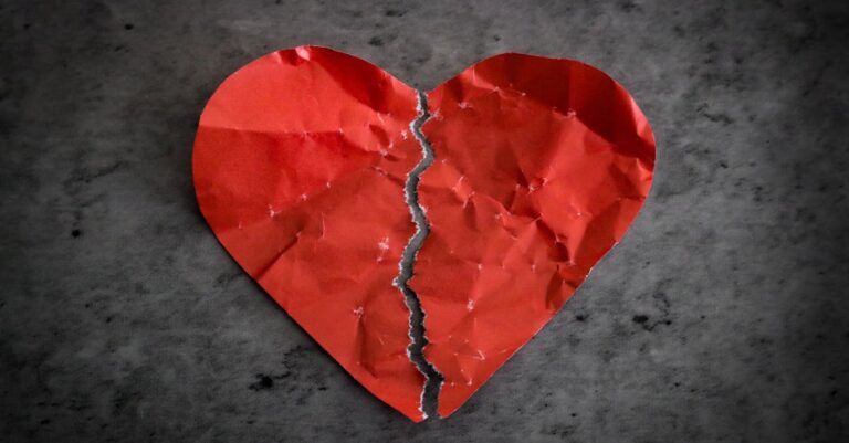 A torn red paper heart symbolizing heartbreak and lost romance.