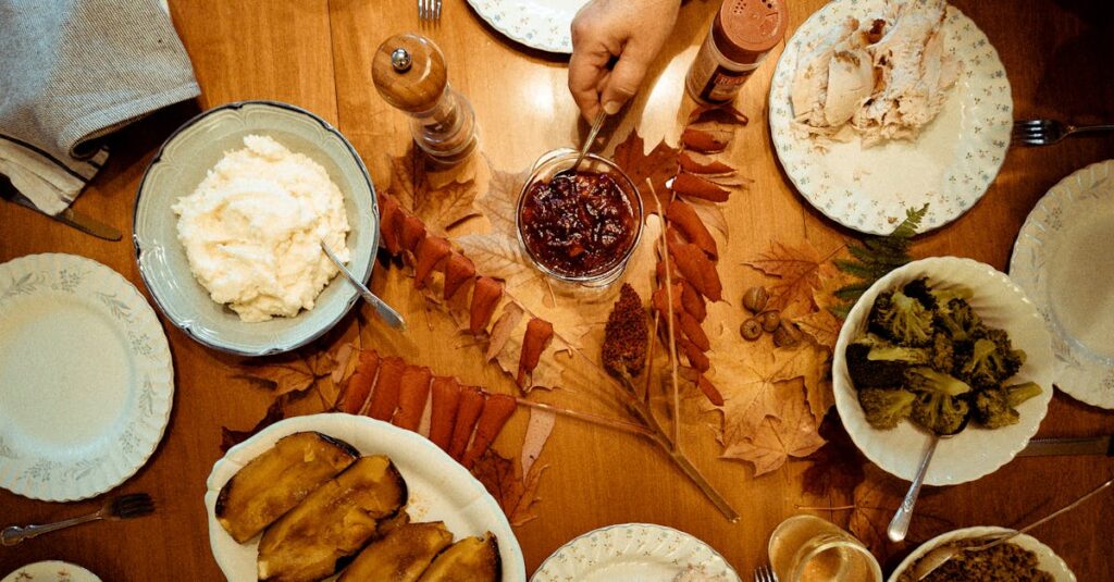 Overhead view of a traditional Thanksgiving dinner table with various dishes and autumn leaves.