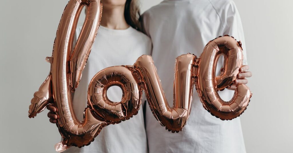 A couple in blank white t-shirts holding a metallic 'love' balloon emphasizing romance and joy.