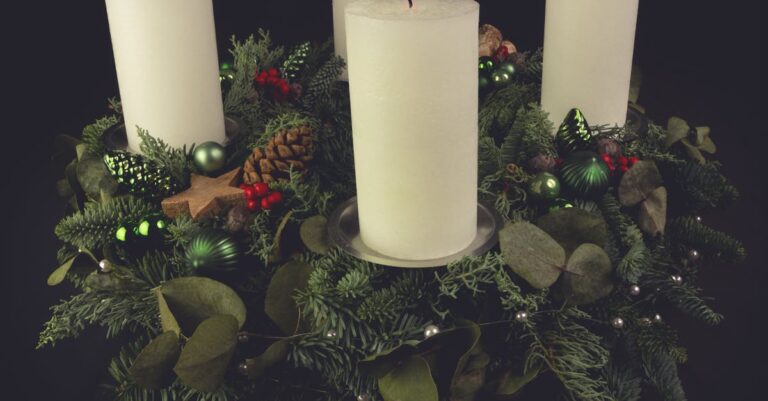 Christmas advent wreath with green foliage, decorated with candles, pinecones, and ornaments.