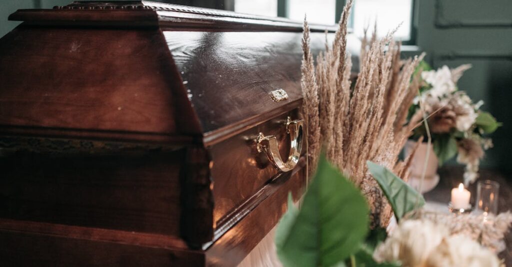 A beautiful funeral display featuring a wooden coffin with flowers and candles indoors.