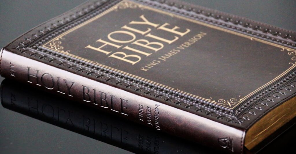 Close-up view of a leather bound King James Version Holy Bible resting on a reflective surface.