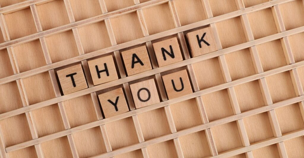 Wooden letter tiles spelling 'thank you' on a grid background, perfect for gratitude themes.