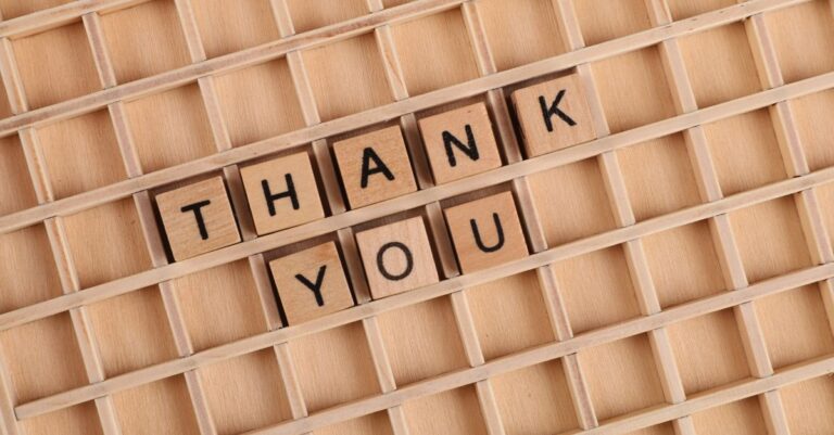 Wooden letter tiles spelling 'thank you' on a grid background, perfect for gratitude themes.