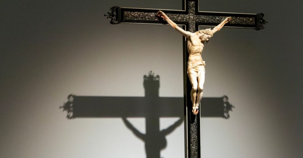 Close-up of a crucifixion figurine casting a shadow on a wall, emphasizing religious art.