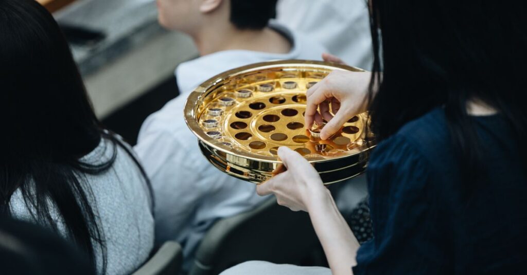 A golden communion plate is passed during a church service, reflecting the act of worship.