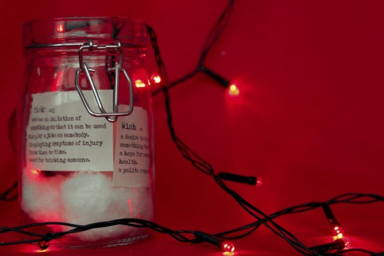 A festive glass jar with cotton and decorative lights on a red background, perfect for Christmas.