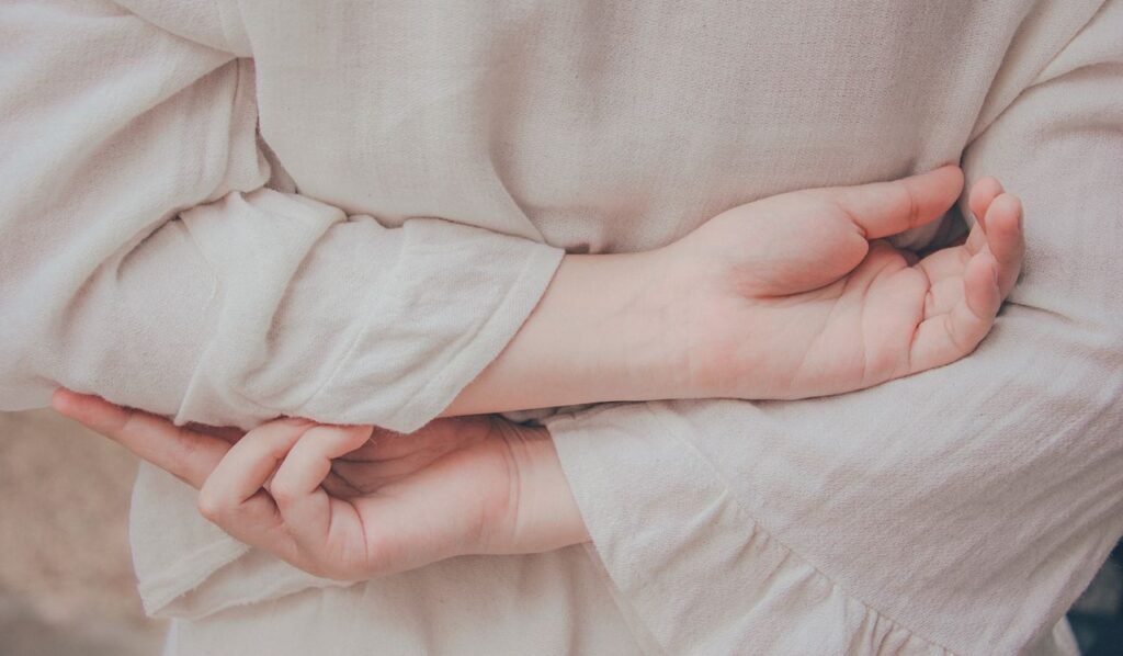 Close-up of intertwined hands wearing beige fabric, offering a serene and minimalistic feel.
