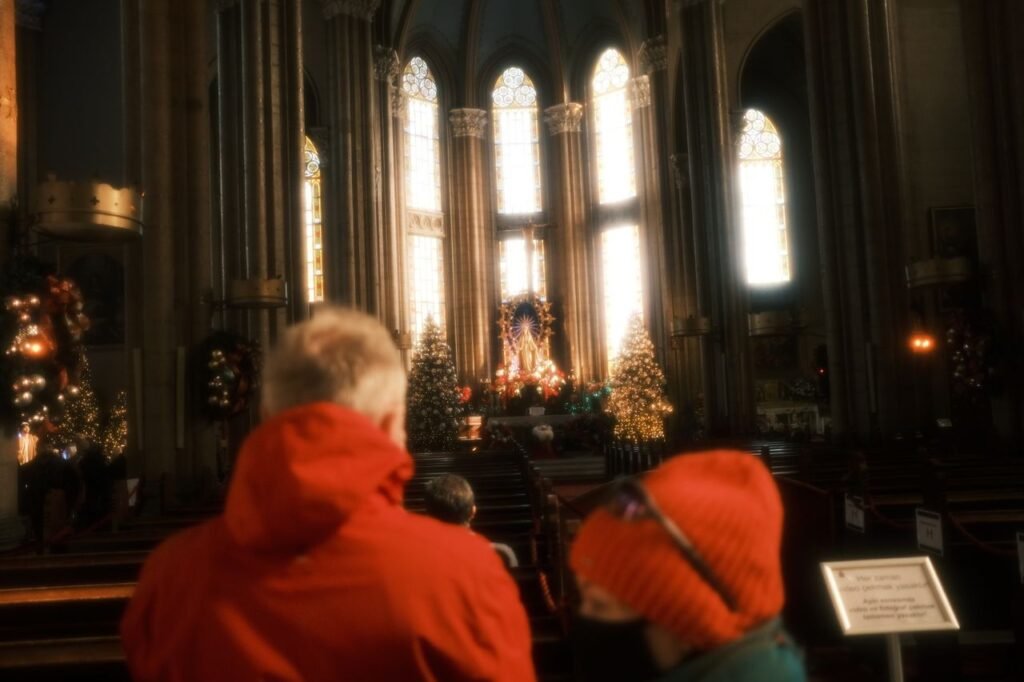 Visitors in a cathedral admire the altar adorned with Christmas decorations and sunlight.