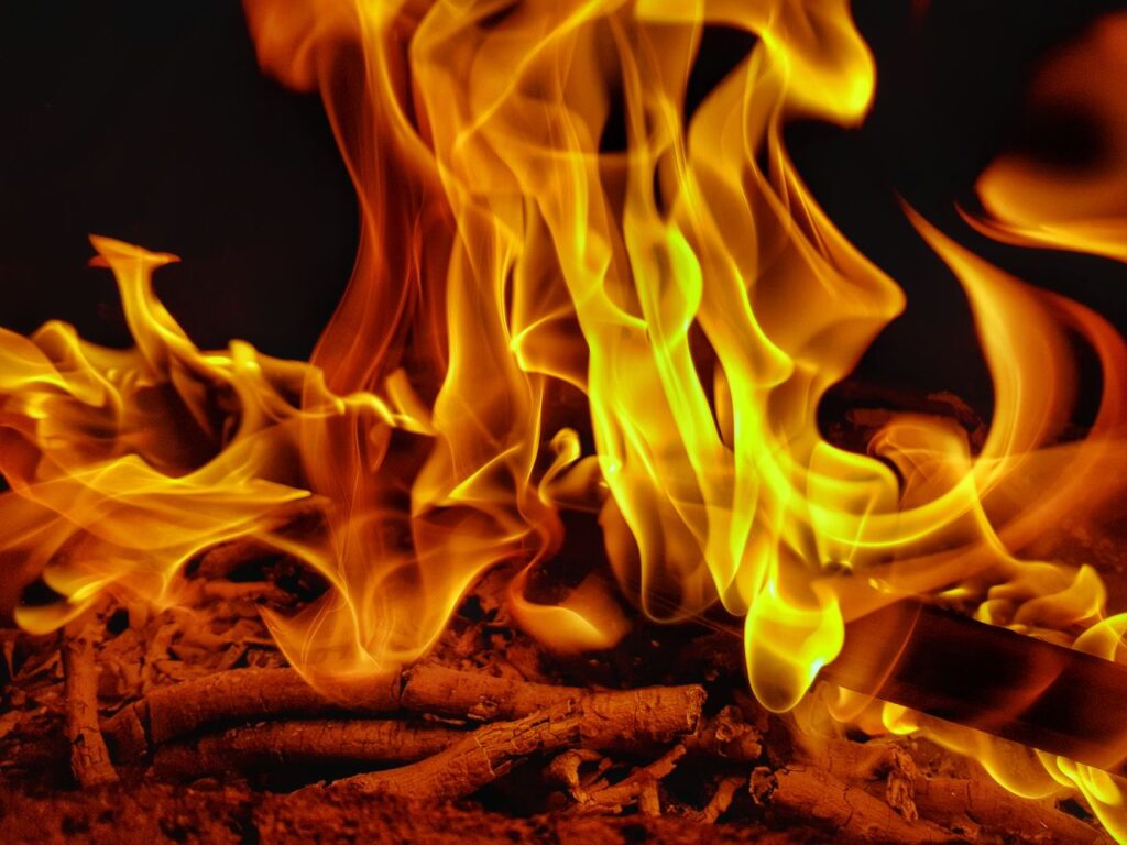 A close-up view of vibrant flames dancing among burning wood, capturing the warmth and intensity of fire.