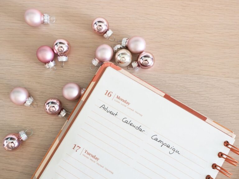 Close-up of a planner with Advent campaign notes and pink baubles.