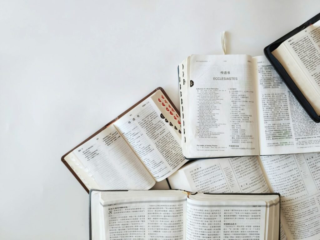 Multiple Bibles open on a white background showing text from Ecclesiastes in different languages.