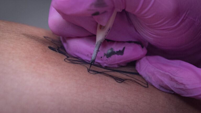 Close-up view of a tattoo artist inking a design on human skin.