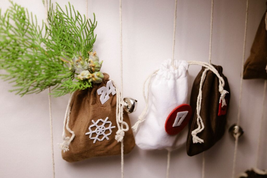 Handmade advent calendar bags with green foliage and festive numbers for holiday decor.