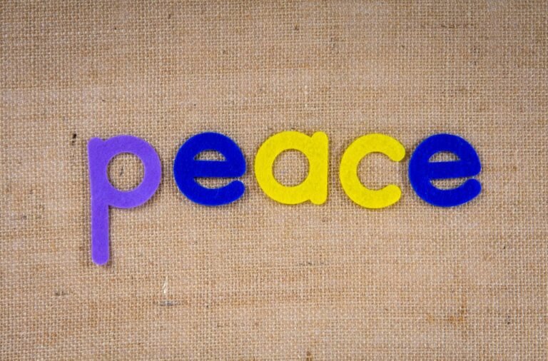 Vibrant letters spelling 'peace' on textured burlap surface.