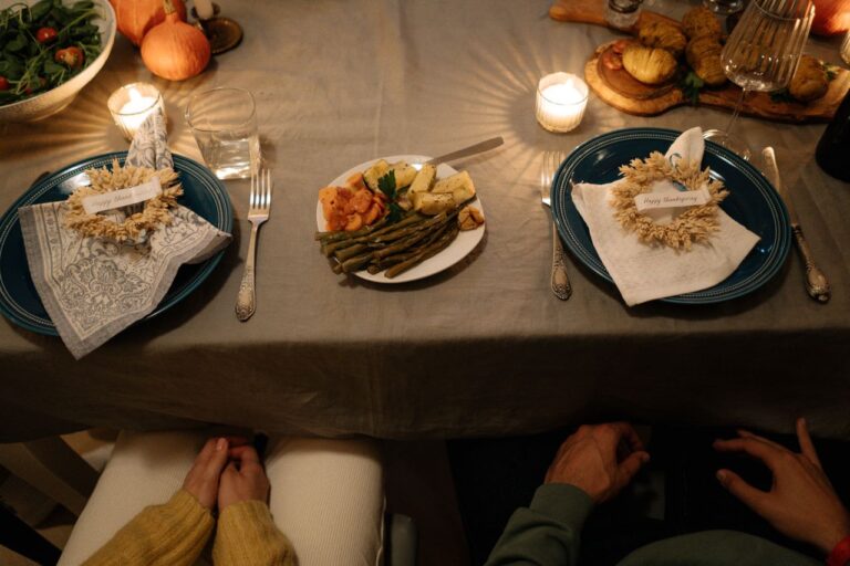 Elegant Thanksgiving dinner setting with candlelights, plates, and festive decor.