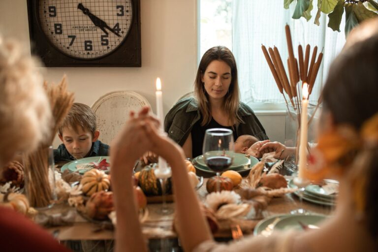 A family gathered around a table for a Thanksgiving feast, sharing a prayer.
