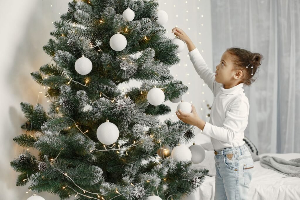 Young girl decorating a Christmas tree indoors, emphasizing holiday spirit and joy.