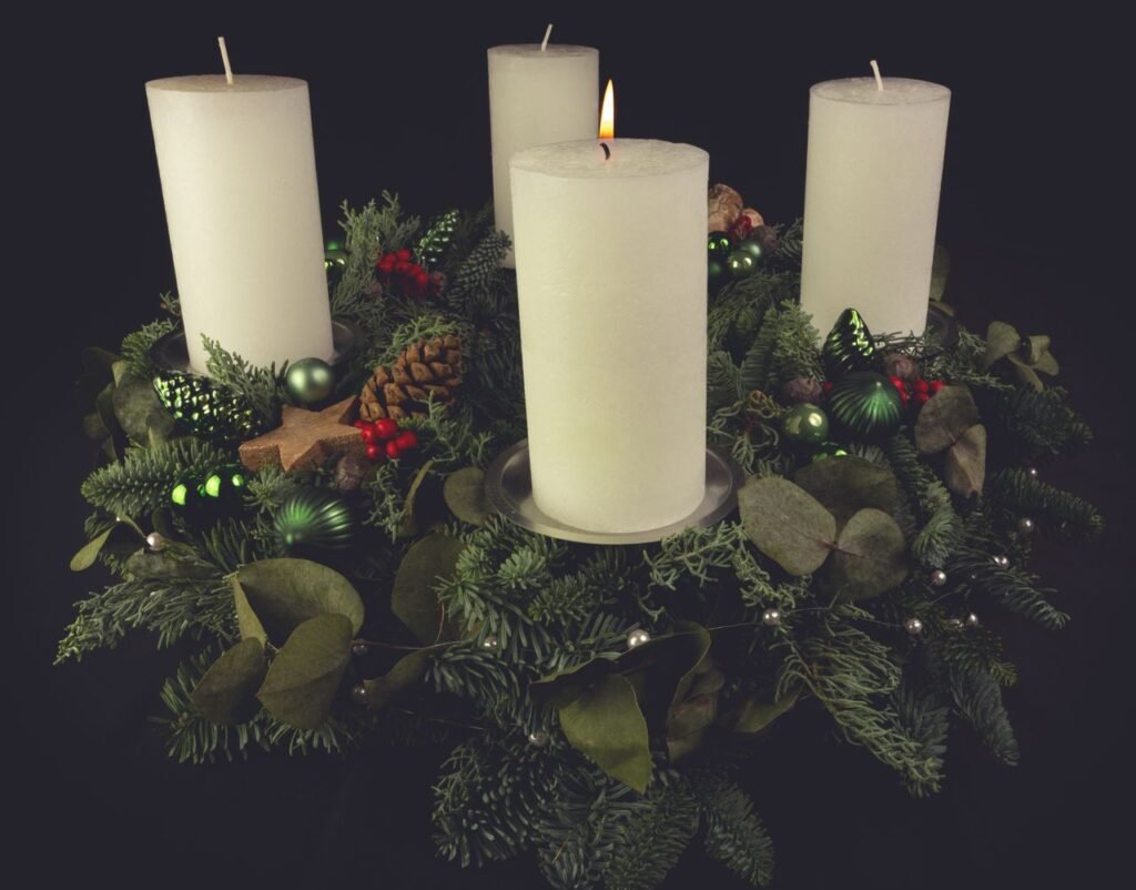 pexels-photo-6002916-6002916-2 Christmas advent wreath with green foliage, decorated with candles, pinecones, and ornaments.