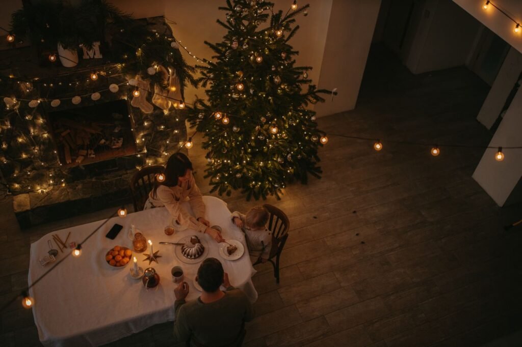 A warm family dinner setting with Christmas decorations including lights, tree, and festive table.