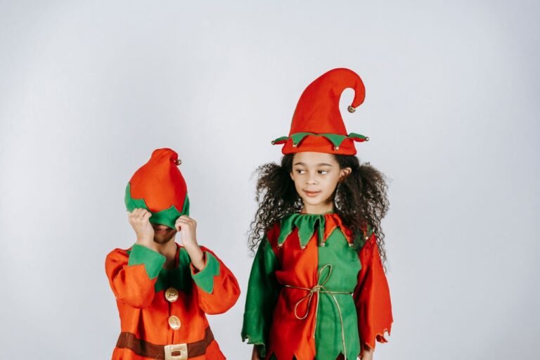 Little African American children in bright red and green costumes of elves celebrating Christmas on white background