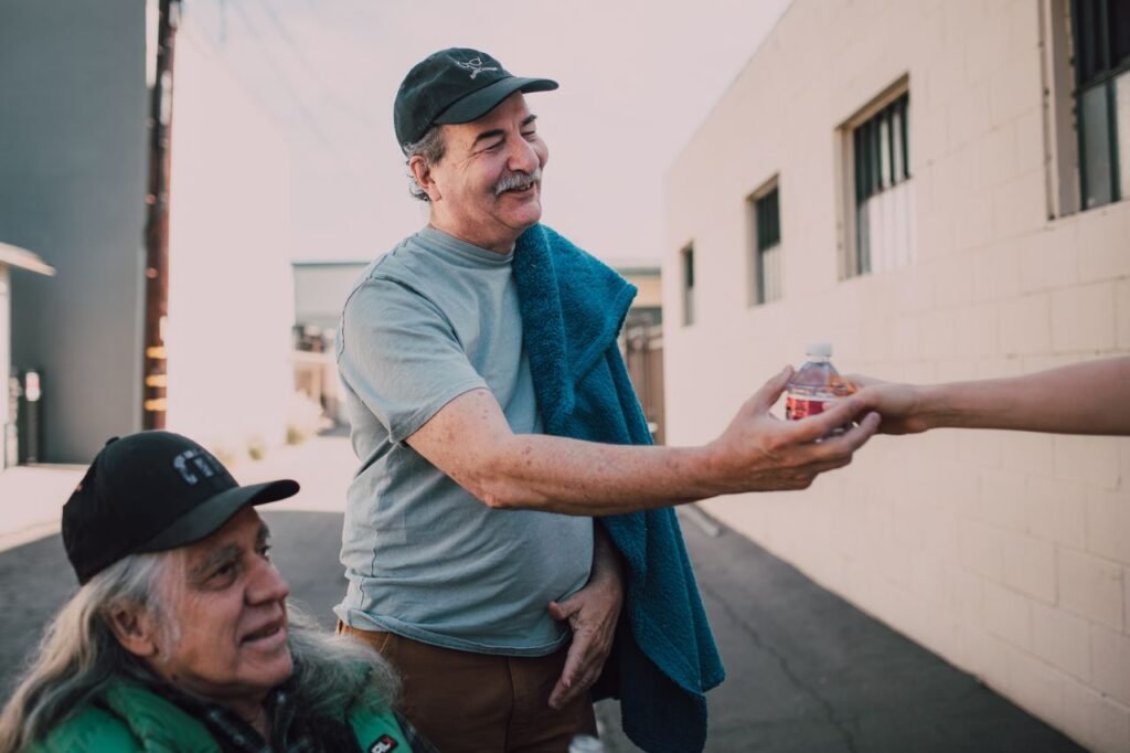 Two adults exchanging bottled water with kindness in an urban setting.