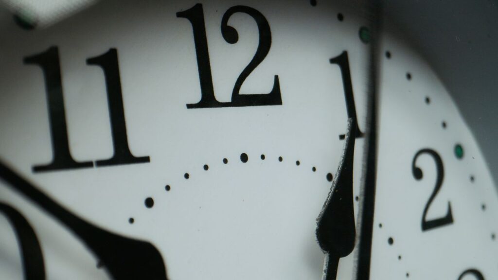 Macro photograph of a clock face showing numbers and minute markers.